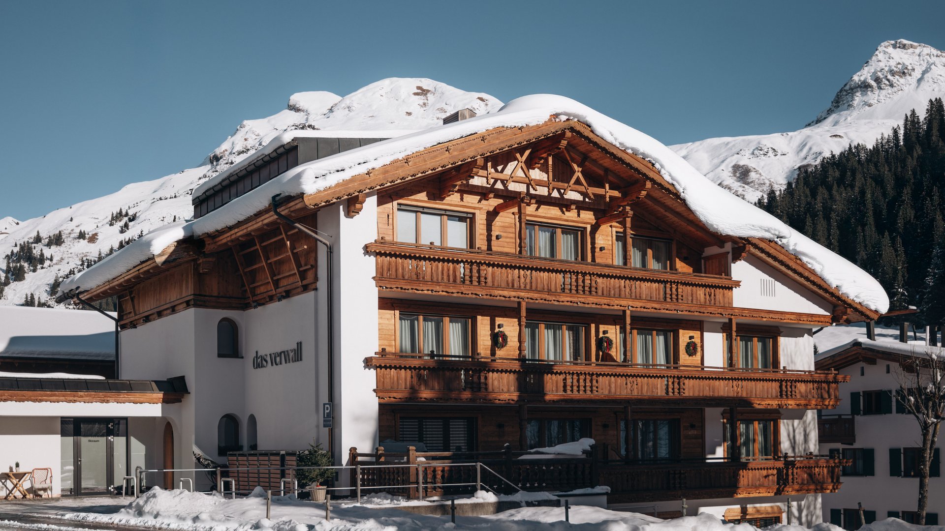 Das Verwall: Spa und Apartment in Lech am Arlberg Verschneites Alpenhotel mit Holzbalkonen vor einer Bergkulisse