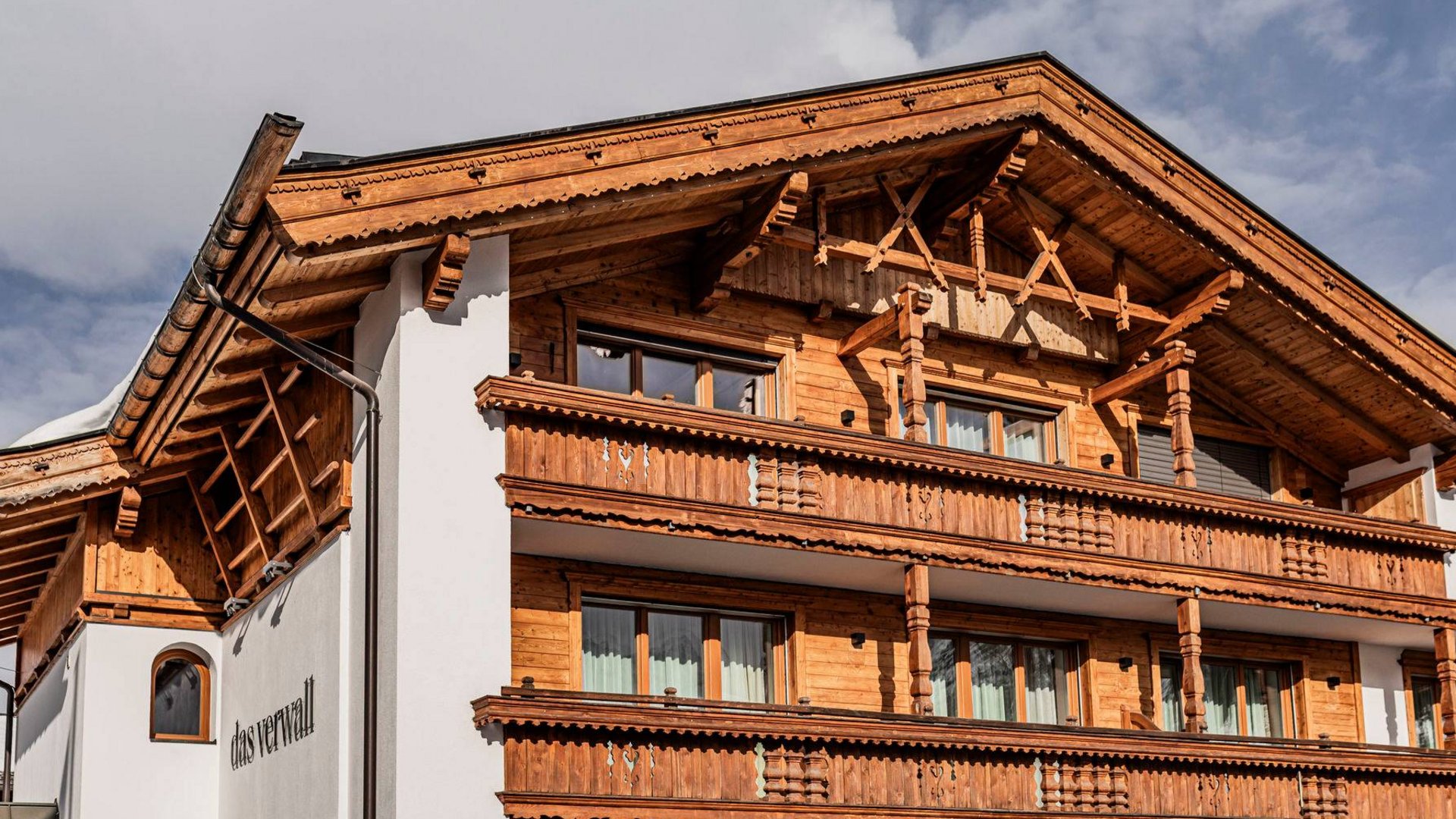 Das Verwall: Spa und Apartment in Lech am Arlberg Traditionelles alpines Haus mit Holzfassade und Balkonen unter bewölktem Himmel
